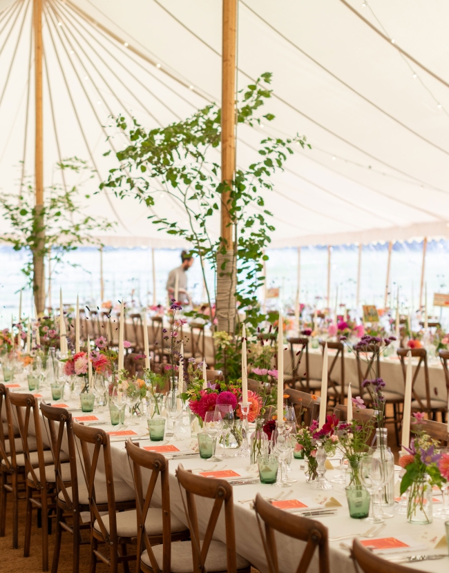 Vibrant pink and green wedding décor and flowers for a marquee wedding in Worcestershire, with trees lining the poles inside a Bohemia Canvas marquee.